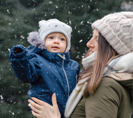 Mom holding her baby outside in the snow to protect babies from germs