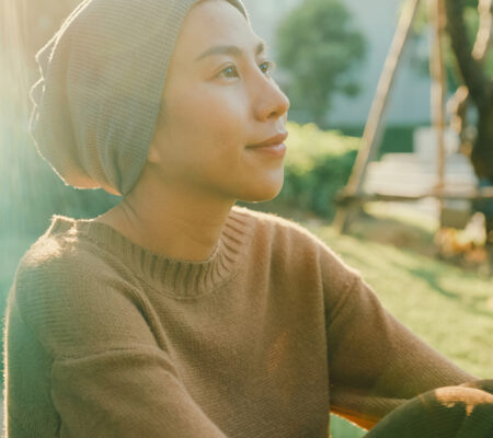 Person with hat sitting outside in the sun going through radiation therapy cancer treatments