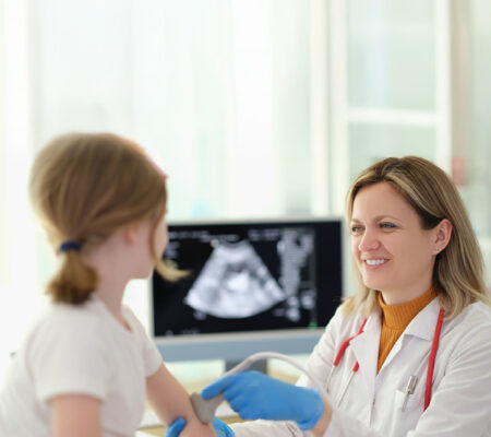 Young girl getting elbow checked out for juvenile idiopathic arthritis on a scan by her doctor.